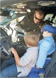  ?? Photo contribute­d by Amy Liggons / Cedartown ?? Sgt. Brad Lloyd shows off all the controls in an Aragon Police Department patrol car to Isaac Hearne and Cohen Chastain.