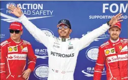  ??  ?? Mercedes' British driver Lewis Hamilton (C) celebrates after winning the pole position next to second placed Kimi Raikkonen (L) and third placed Sebastian Vettel.