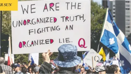  ?? DAVE SIDAWAY / POSTMEDIA NEWS ?? A man holds a QAnon sign during a protest against the Quebec government's mandatory mask law in Montreal in September.