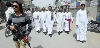  ??  ?? LAHORE: In this photograph, a private security guard escorts Christian priests in the congested neighborho­od of Youhanabad in Lahore. —AFP