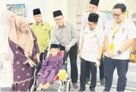  ?? ?? GEMBIRA: Mohamad Akif Mohd Norhaizan, 8, ditemani ibunya Rosma Daud (dua kiri) menerima bantuan kerusi roda sumbangan JKMS yang disampaika­n oleh Razi (empat kiri) pada majlis itu semalam.