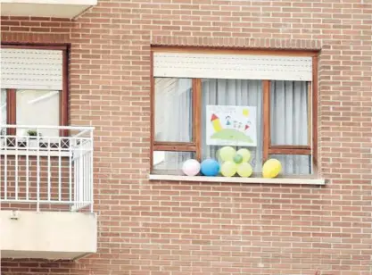  ??  ?? Un dibujo y varios globos en la ventana de una casa durante el confinamie­nto.