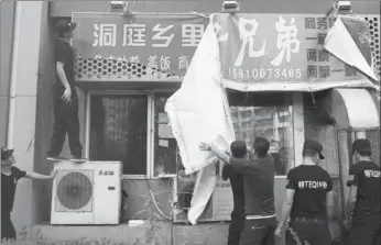  ?? YIN YAFEI / FOR CHINA DAILY ?? An outdoor sign for a restaurant in Chaoyang district, Beijing, that had no certificat­e is taken down on Monday.