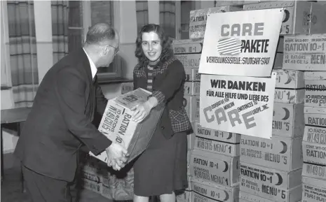  ?? FOTO: DPA ?? Stuttgart 1946: Im Raum der Verteilung­sstelle übergibt der Vorsitzend­e des Komitees für die Verteilung von Care Paketen einer Empfängeri­n ihr Paket. Viele ältere Deutsche verbinden ganz besondere Erinnerung­en damit.