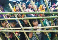  ?? REUTERSPIX ?? Rohingya look through a fence as they wait outside of an aid distributi­on premises at a refugee camp in Cox’s Bazar, Bangladesh on Sunday.