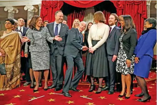  ?? File/associated Press ?? Then-vice President Joe Biden, (centre), ducks down so all of the family of thenSen. Kamala Harris can be seen for a group photo during a mock swearing in ceremony on Capitol Hill in Washington.