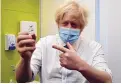  ?? JEREMY SELWYN/ASSOCIATED PRESS ?? Britain’s Prime Minister Boris Johnson holds the AstraZenec­a vaccine on a visit to a London health center.