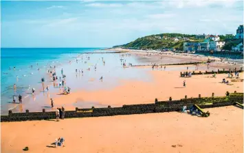  ??  ?? A view from the pier showing people enjoying a paddle on a warm day at Cromer’s spacious beach beneath the cliffs.