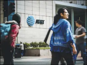  ?? BRANDON THIBODEAUX / THE NEW YORK TIMES ?? Pedestrian­s pass by the AT&amp;T corporate headquarte­rs in Dallas. After the 2017 tax law was passed, the company handed out worker bonuses and contribute­d to its employee and retiree medical trust fund. But it also appears AT&amp;T is shedding employees.