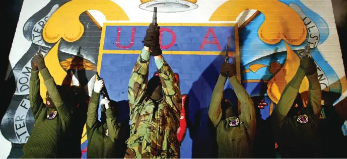  ?? Photo: Reuters ?? Loyalist gunmen fire their weapons in a show of strength in front of a sign for the Ulster Defence Associatio­n in the Protestant heartland Shankill Road area of central Belfast in 2002.