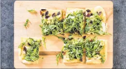  ?? AMERICA’S TEST KITCHEN VIA AP ?? Pesto flatbread with artichokes, olives and arugula from recipe appears in the cookbook “Dinner Illustrate­d”.