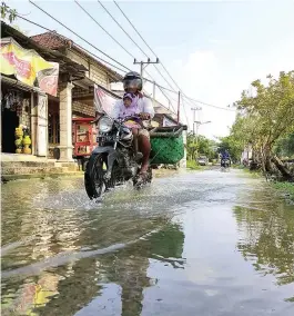  ?? JAWA POS RADAR LAMONGAN ?? DAMPAK SIKLON: Air meluber menggenang­i jalanan di Desa Sukosongo akibat luapan aliran Kali Gempol.