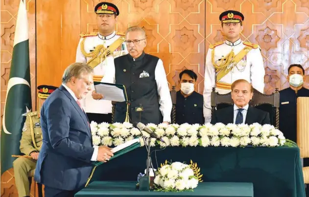  ?? ?? ±
President Arif Alvi (centre) administer­s oath of office to FM Ishaq Dar as Shahbaz Sharif watches during a ceremony in Islamabad on Wednesday.