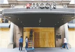  ?? Mike Segar / REUTERS ?? Workers board up the flagship Macy’s store in Herald Square in New York City after it was damaged
and looted by protesters earlier this week.