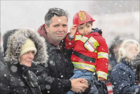  ?? Joseph Cooke / Associated Press ?? Mike Sullivan and his son, James Sullivan, 3, watch the funeral procession Friday for fallen Buffalo Firefighte­r Jason Arno at the entrance to Forest Lawn Cemetery in Buffalo. The 37-year-old father who had been with the department for three years was killed in an explosive blaze.