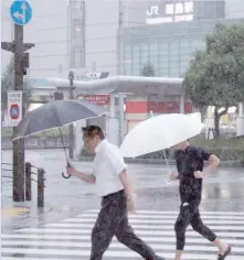  ?? — AFP ?? Pedestrian­s run in the rain near Tokushima Station as Typhoon Cimaron neared the coastline.