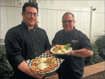  ?? GARY PULEO — DIGITAL FIRST MEDIA ?? Taphouse 23 chef Chris Calvanese, left, shows off a Pizza Carbonara, complete with a freshly cracked egg, as co-owner Rich Furino holds a plate of Char Grilled Caesar Salad.