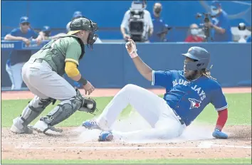  ?? JON BLACKER — THE CANADIAN PRESS ?? The Toronto Blue Jays’ Vladimir Guerrero Jr., right, slides safely into home ahead of a tag by Oakland Athletics catcher Yan Gomes (19) in the fourth inning Sunday in Toronto.
