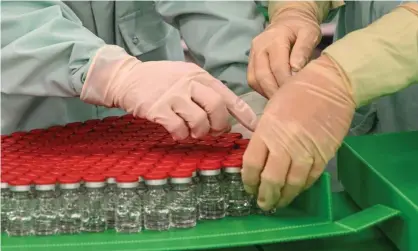  ?? Photograph: Vincenzo Pinto/AFP/ Getty ?? Lab technician­s handle vials during tests for the production of Oxford University’s Covid-19 vaccine.