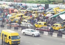  ?? ?? Commuters board yellow painted mini buses, popularly called Danfo, parked at the Ojodu-Berger bus station in Lagos, Nigeria’s commercial capital.