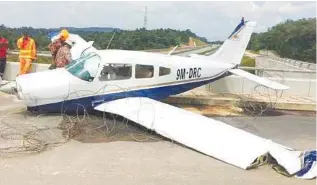  ??  ?? Firefighte­rs inspect the damaged light aircraft that crashed near the Malaysia-Singapore Second Link.