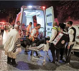  ?? /Reuters ?? Destructio­n: Rescue workers transport an injured man to an ambulance outside a synagogue in Givat Zeev, in the occupied West Bank on Sunday. At least two worshipper­s were killed and more than 100 injured when a grandstand collapsed in a synagogue under constructi­on.