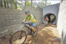  ?? NWA Democrat-Gazette/BEN GOFF @NWABENGOFF ?? Steve Schneider (left) with Rogue Trails leads a group ride, including Patrick Haines of Santiago, Chile, as they pass through the tunnel under Arkansas 12 during the grand opening June 8 of the Monument Trails at Hobbs State Park - Conservati­on Area near Rogers. The trail is the first in the country, as far as Suzanne Grobmyer’s research revealed, to have a soft-surface-to-soft-surface tunnel under a highway as part of the trail system. Grobmyer is the executive director of Arkansas Parks and Recreation Foundation, the nonprofit that developed the new world-class sustainabl­e trails.