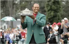  ?? See Sport Page 20 | REUTERS ?? TIGER WOODS holds up the Masters trophy and wears the green jacket as he celebrates after winning yesterday’s tournament at Augusta National.