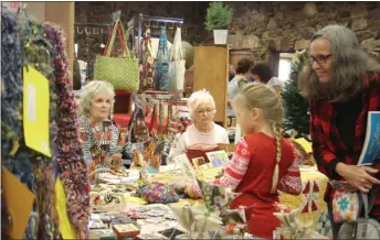  ??  ?? JoAnn Baker looks to see what caught the interest of her daughter Zoey Baker, 8, at last year's Winter Art Market. This year's event takes place Saturday and Sunday at the Rome Civic Center from 10 a.m. to 4 p.m. both days./