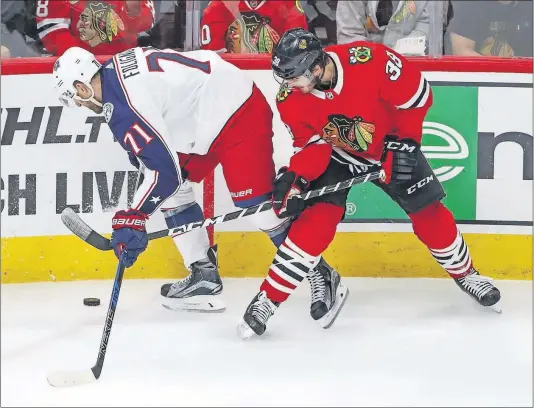  ?? [KAMIL KRZACZYNSK­I/THE ASSOCIATED PRESS] ?? The Blue Jackets’ Nick Foligno tries to keep the puck away from Blackhawks left wing Ryan Hartman during the first period Saturday night in Chicago.