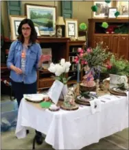  ?? BY SHAWN MEANS — THE ASSOCIATED PRESS ?? This photo provided by Amy McLaughlin taken at the Teays Valley ReStore in Hurricane, W.V., shows Marisa Jackson, artist, calligraph­er and owner of MarisaMade, explaining the inspiratio­n behind her tablescape. Marisa used wooden chargers, spring...