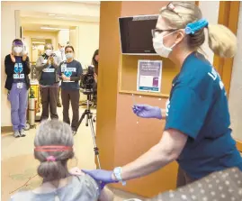  ?? RACHAEL PACELLA/CAPITAL GAZETTE ?? People clap after epidemiolo­gist Mary Clance receives her first dose of the Pfizer COVID-19 vaccine Monday at Anne Arundel Medical Center.