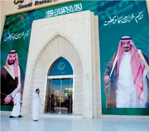  ?? (Faisal Al Nasser/Reuters) ?? MEN WALK by posters depicting Crown Prince Muhammad and King Salman in Riyadh on Thursday.