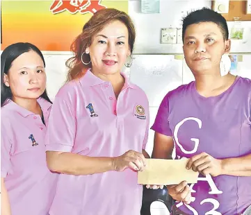  ??  ?? Loh (centre) hands over a RM10,000cheque to Wong while UPP Dudong Women Section secretary Karen Cho looks on.