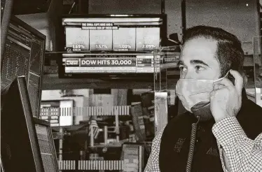  ?? Nicole Pereira / Associated Press ?? A trader at the New York Stock Exchange works at his terminal Tuesday. By closing bell, the Dow Jones industrial average shot up nearly 455 points, or 1.5 percent, to 30,046.24.