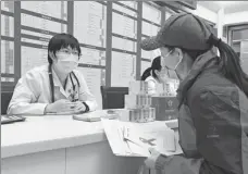  ?? REN CHAO / XINHUA ?? A medical profession­al with Beijing Haidian Hospital introduces material on AIDS prevention to a visitor during a free consultati­on event in Beijing on World AIDS Day on Dec 1.