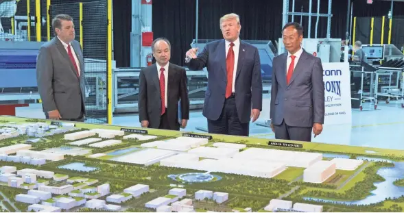  ?? MARK HOFFMAN / MILWAUKEE JOURNAL SENTINEL ?? President Trump, Softbank CEO Masayoshi Son (second from left) and Foxconn chairman Terry Gou (right) examine a model of the factory being developed during the ceremonial groundbrea­king for Foxconn’s factory in Mount Pleasant.