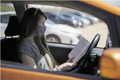  ??  ?? Skylar Richmond Friesen reads a book while she waits during her 15-minute observatio­n period Friday after she received her first dose.