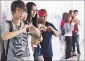  ?? Mak Remissa European Pressphoto Agency ?? WELL-WISHERS at Kuala Lumpur’s airport pose for pictures next to a message mural for those aboard Malaysia Airlines Flight 370, now missing for a week.