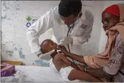 ?? FARAH ABDI WARSAMEH — THE ASSOCIATED PRESS ?? Dr. Mustaf Yusuf treats Ali Osman, 3, as his mother, Owliyo Hassan Salaad, 40, holds him at a malnutriti­on stabilizat­ion center in Mogadishu, Somalia, on Sunday.