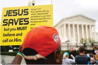  ?? STEFANI REYNOLDS/AFP VIA GETTY IMAGES ?? A person holds a “Jesus Saves” sign outside the U.S. Supreme Court, which ruled in favor of a praying football coach.