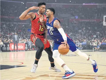  ?? AP ?? Clippers forward Paul George, right, drives the ball to the basket as Hawks forward De’Andre Hunter defends.