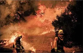  ?? NOAH BERGER/AP ?? Crews light a backfire to prevent a blaze from jumping a road Saturday near Ventura, Calif.