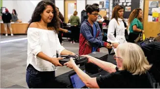  ?? JASON GETZ / SPECIAL TO THE AJC ?? Cross Keys junior Lesly Chavez (left) receives a Chromebook laptop from DeKalb County Schools informatio­n technology employee Mary Isle during the Chromebook distributi­on Thursday at Cross Keys High School. Students paid a $20 fee for insurance on the devices.