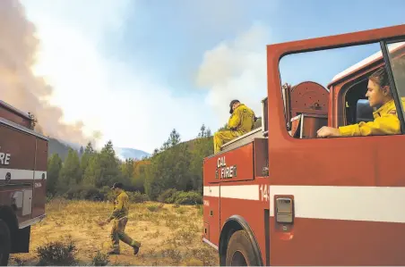  ??  ?? Daniel Frazee (left), Charles Schindler and Kassidy Harms watch helicopter­s dump water on the fire outside of Geyservill­e.