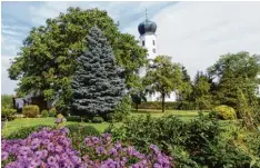  ??  ?? Versteckt hinter Bäumen und Blumen ist die Kirche Fronhofen zu sehen. Je nach Jah reszeit ein Hingucker.