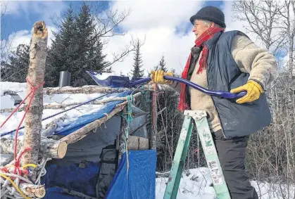  ?? SANDRA PHINNEY ?? Nina Newington clears snow off the roof of an enclosure forest harvest protesters have erected as part of their encampment on South Mountain in Annapolis County.