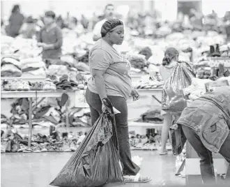  ?? Associated Press ?? Hurricane Harvey flood evacuees look through supplies at a shelter set up inside NRG Center.