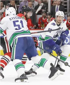  ?? JONATHAN DANIEL/GETTY IMAGES ?? The Hawks’ Brendan Perlini tries to split the defense of the Canucks’ Troy Stecher and Jay Beagle on Monday at the United Center.