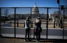  ?? Al Drago/Getty Images ?? People view the U.S. Capitol, behind security fencing, on Sunday in Washington, D.C. The National Guard has increased security at the Capitol and across the nation where far-right groups have threatened violence leading up to President-elect Joe Biden’s inaugurati­on.